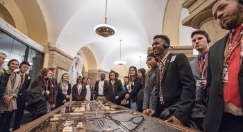 A photo of a group of students wearing headphones around a table of artifacts.