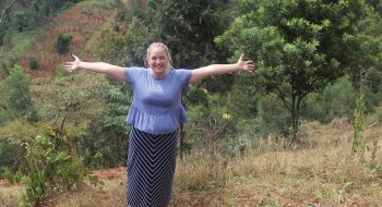 A photo of St Lawrence student Hannah Markey posing in front of a lush green landscape with her arms outstretched.