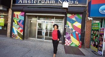St Lawrence Trustee Elinor Tatum standing outside a colorful building in New York City that reads &quot;Amsterdam News&quot;.