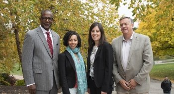 A photo of a group of four St Lawrence alumni smiling with a bunch of trees in the background.