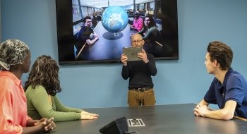 Eric Williams-Bergen showing sophomores new augmented reality software, this one rendering a globe between students while on camera.