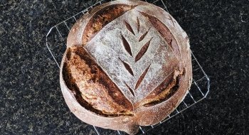 A close up photo of a freshly baked loaf of bread with a leaf design cut into the top.