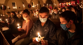 A photo of students sitting in the chapel lighting candles together.