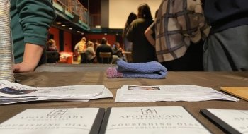 A close up of Apothecary chocolate bars with fliers about chocolate and students in the background.