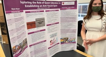 Skylar stands next to a poster displaying her research