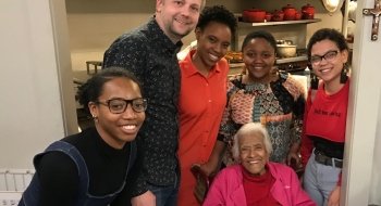 A group of students gather for a photo with legendary New Orleans chef Leah Chase in her kitchen.