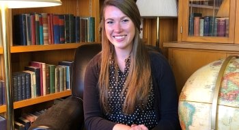 Headshot of Caroline Fleischauer sitting on a leather chair in front of a bookcase.