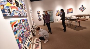 A group of Saint Lawrence students, holding notebooks, look at artwork on the wall of the Richard F Brush Art Gallery
