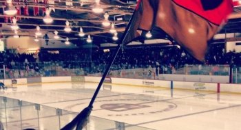 Evan waiving a Saints scarlet and brown flag at Appleton Arena