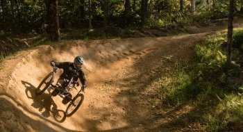 A person rides an all terrain bicycle on a dirt trail in the woods.