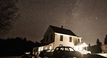 The starry night sky over a white farm house.