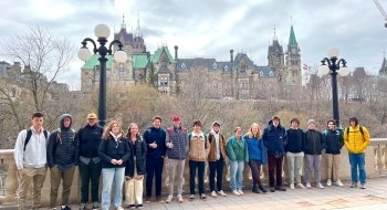 STUDENTS AND JOSEPH JOCKEL STANDING ALONG THE RIDEAU LOCKS, WITH PARLIAMENT IN THE BACKGROUND
