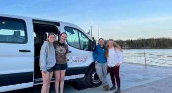 two female students and two female faculty standing next to SLU Van on fairy
