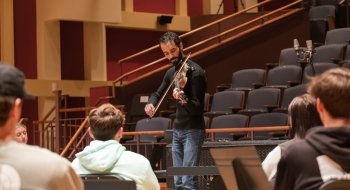 Jake Blount plays the violin to a group of students.