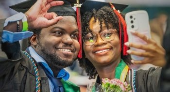 Photo of two graduates taking a selfie, smiling and celebrating after the graduation 2024 ceremony.
