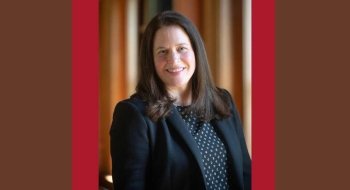 Headshot of Kim Hissong, with shoulder-length brown hair and wearing a black blazer over a patterned blouse.