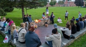 A group of Saint Lawrence students sit around a campfire as part of the First-Year program.