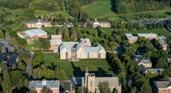 An aerial view of the Saint Lawrence University campus on a sunny day. The campus buildings are surrounded by lush green grass.
