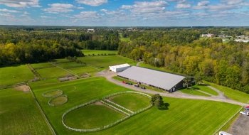 An aerial view of the Saint Lawrence University riding center. The grass and surrounding trees are vibrant green.
