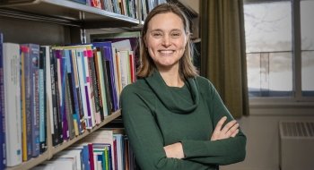 Leah Rohlfsen smiling by a bookshelf