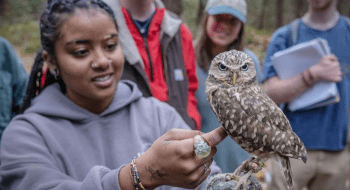 Saint Lawrence University student touching what appears to be a small owl