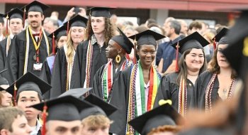 A row of St. Lawrence University standing in a line. They have on caps, gowns, a colorful reflecting their achievements.