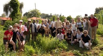 A group of smiling people gather together outside on a sunny day in Kenya.