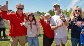 A group of Saint Lawrence University alumni and parents smile and hold up the number 1 with their fingers.
