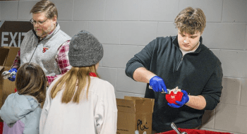 Connor Simons '28 serving scoops of Pub Cookie Crunch to local hockey fans at the Route 11 Rivalry game
