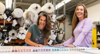 Carey Scully Strobeck and her creative partner laugh while looking at fabric samples.