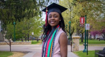 Class of 2026 grad Francesca Mnenula poses on campus accessorized in graduation cap and cords