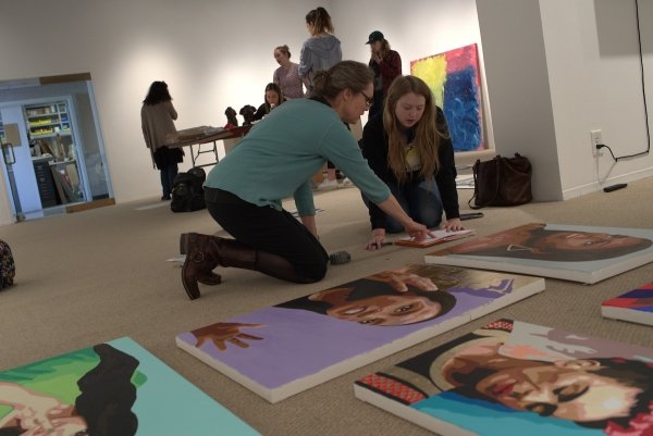 A student discusses her artwork in the gallery with her profesor.