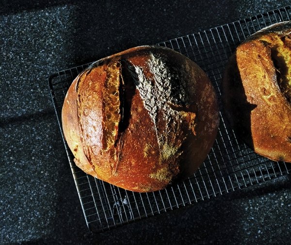 A photo taken from above of two freshly baked loaves of bread on a metal cooling tray.