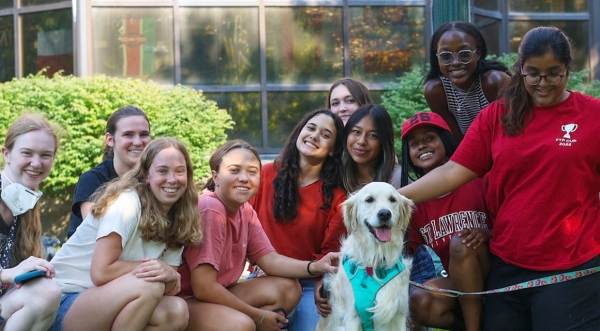 A group of Saint Lawrence students gather around a golden retriever during a "Doggie Destress" wellness event.
