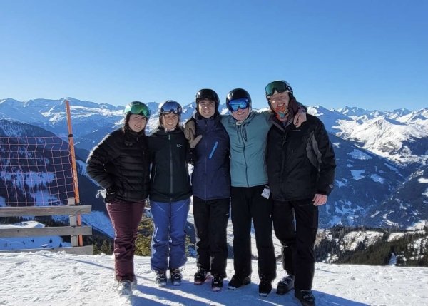 Five students stand on a snowy mountain top.