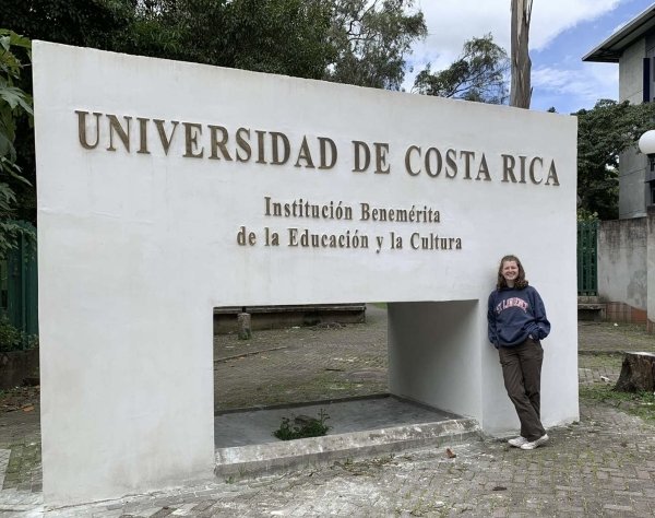 A student stands by the sign for the University of Costa Rica