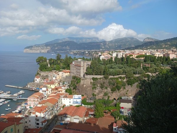 A panoramic view of Sorrento houses with red tile roofs and the ocean.