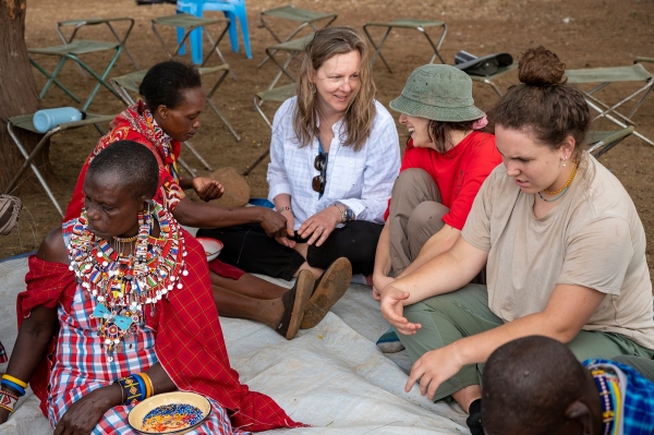 President Morris sits on the ground with a student and chats with local people in Kenya.
