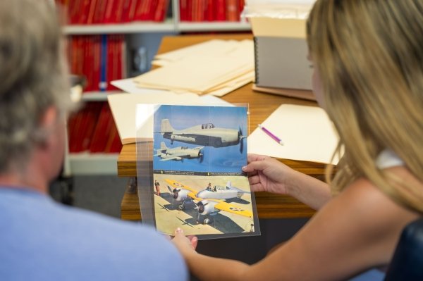 Looking over Meghan's shoulder at two archival photos of WWII fighter planes.