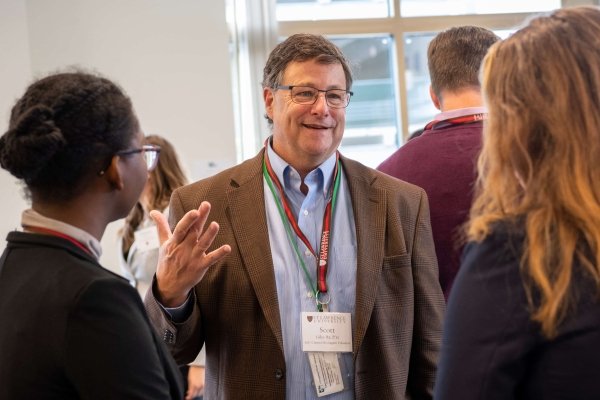 Scott Giles, wearing a Saint Lawrence lanyard, converses with two students at a networking event.
