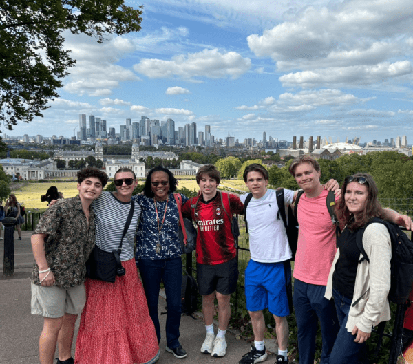 A group of students and the London Faculty Director stand in front of the city skyline