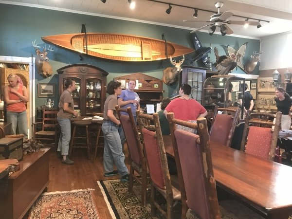 Arcadians singing together around the piano in Unique Antiques.