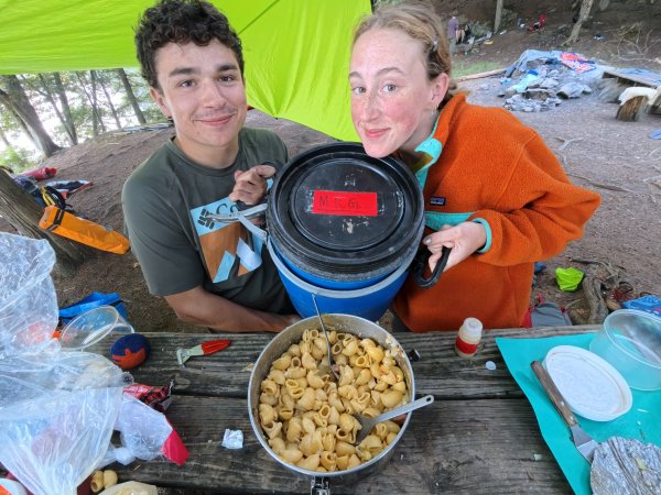 Izzy Kinsella and Luke McChesney holding Mr. G, as the red cook group enjoys some mac-and-cheese.