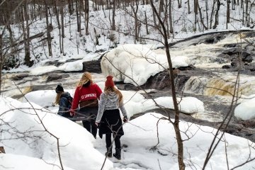 St. Lawrence students walking in the snow near a stream