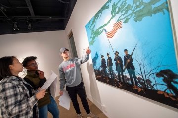 Three students contemplate a piece of art in a gallery.