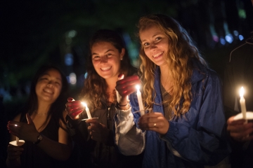 Students holding candles at night. 
