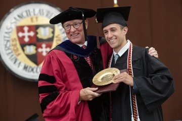 President Emeritus Fox smiles with Brendan Reilly as he hands him a gold plate for his award.