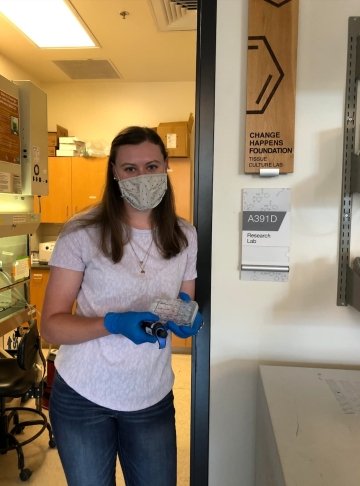 Cora Ferguson, class of 2023, stands in the doorway of the tissue culture lab at Colorado University. She holds a small tray of samples.