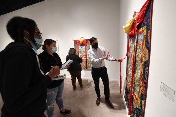 religious studies class examines a thangka painting in the gallery