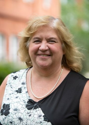 Headshot of Florence Hines, wearing a pearl necklace and a black and white floral blouse.
